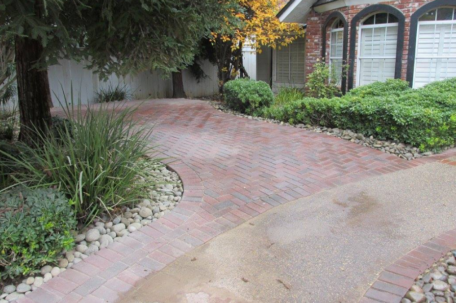 A driveway with bricks and rocks leading to a house.