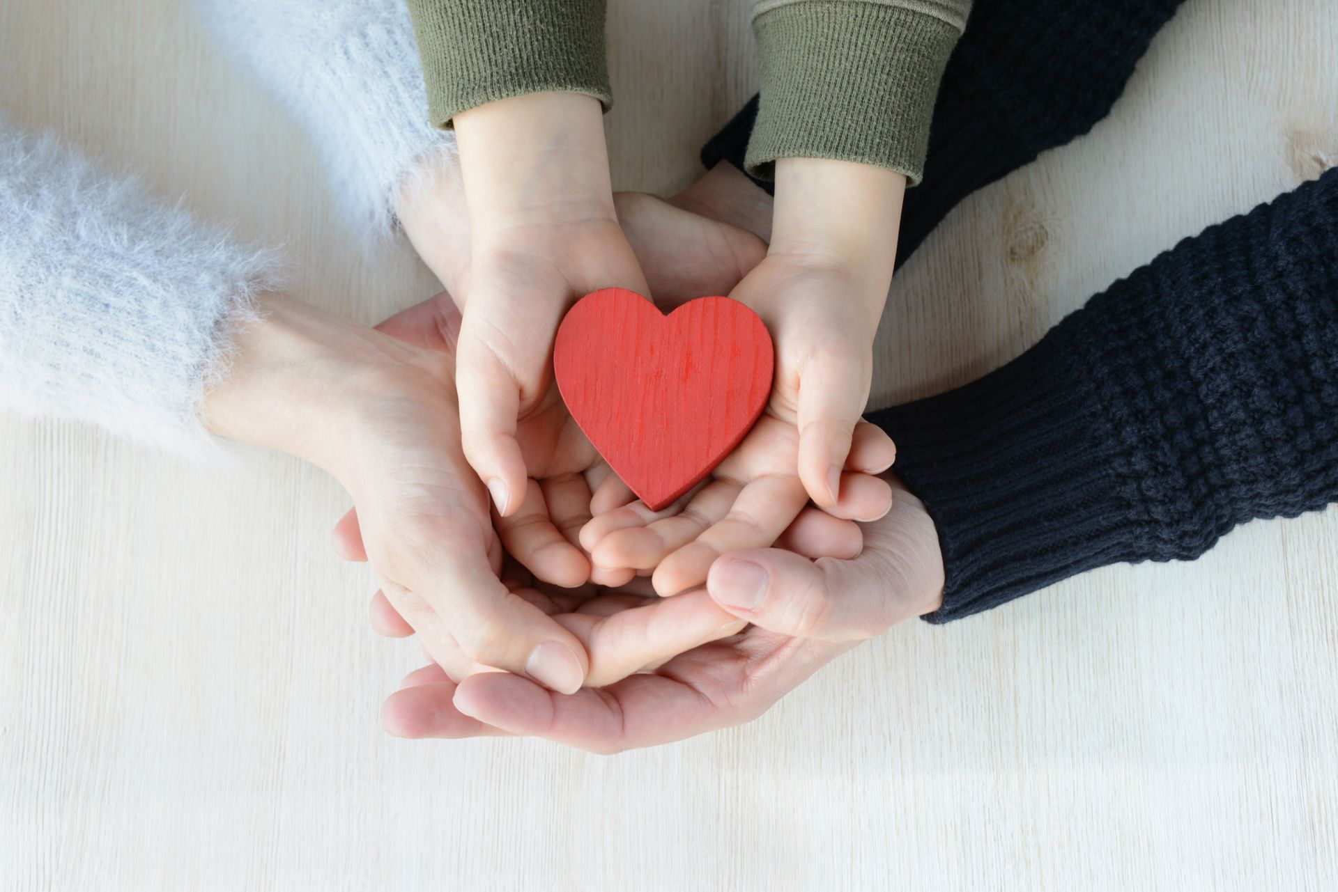 Parents and child holding a red heart symbolizing child support and family care