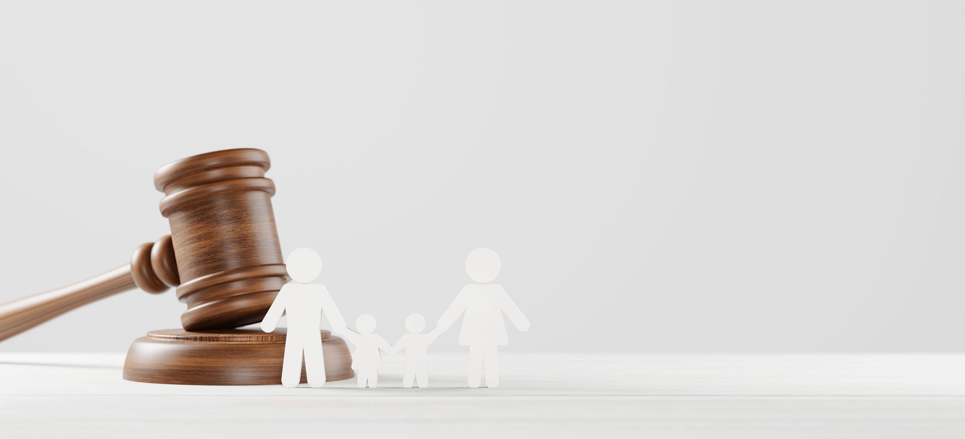 Wooden gavel beside small white figures on a desk, symbolizing legal justice