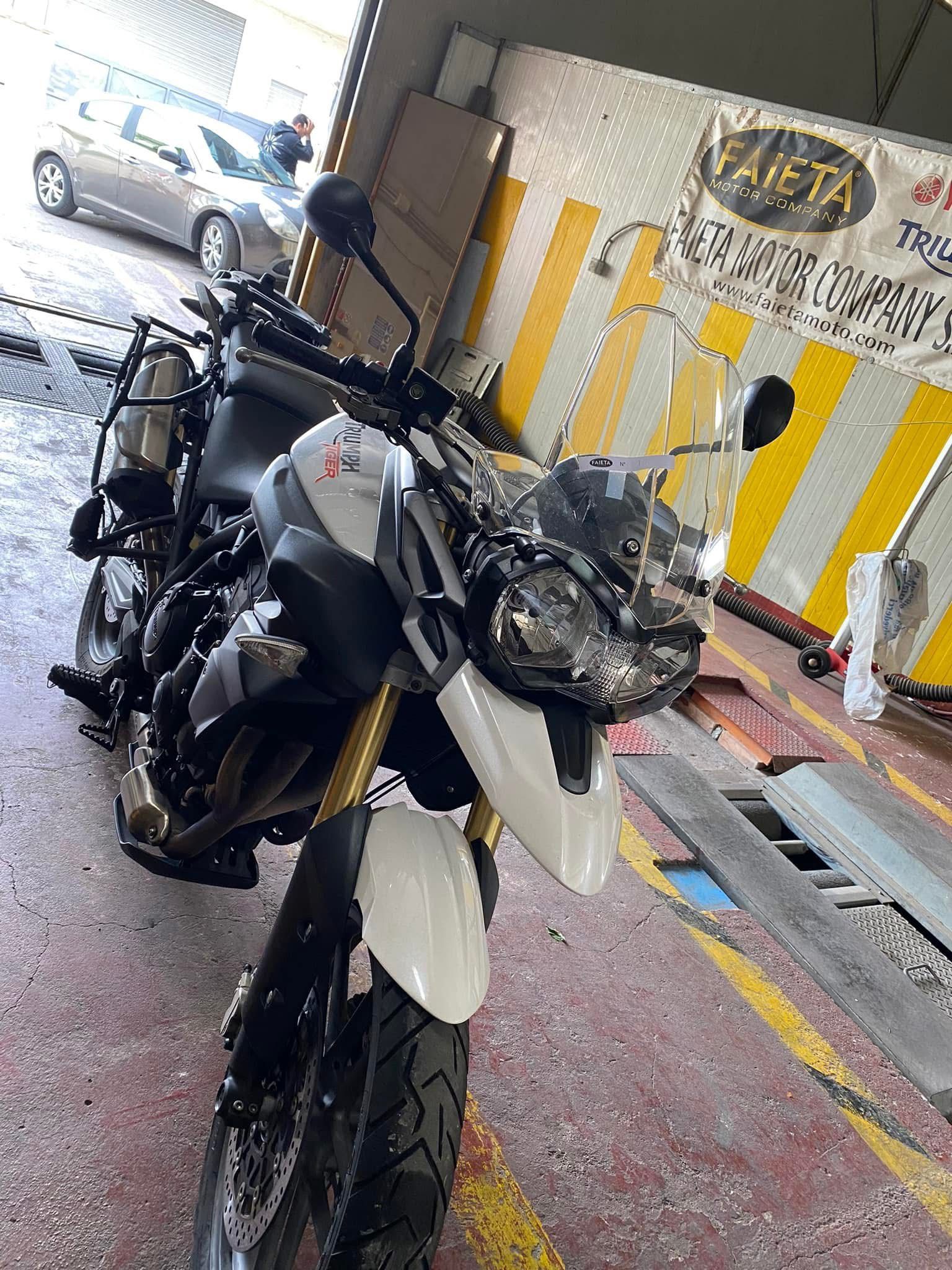 Motocicletta Triumph Tiger bianca e nera in un garage.