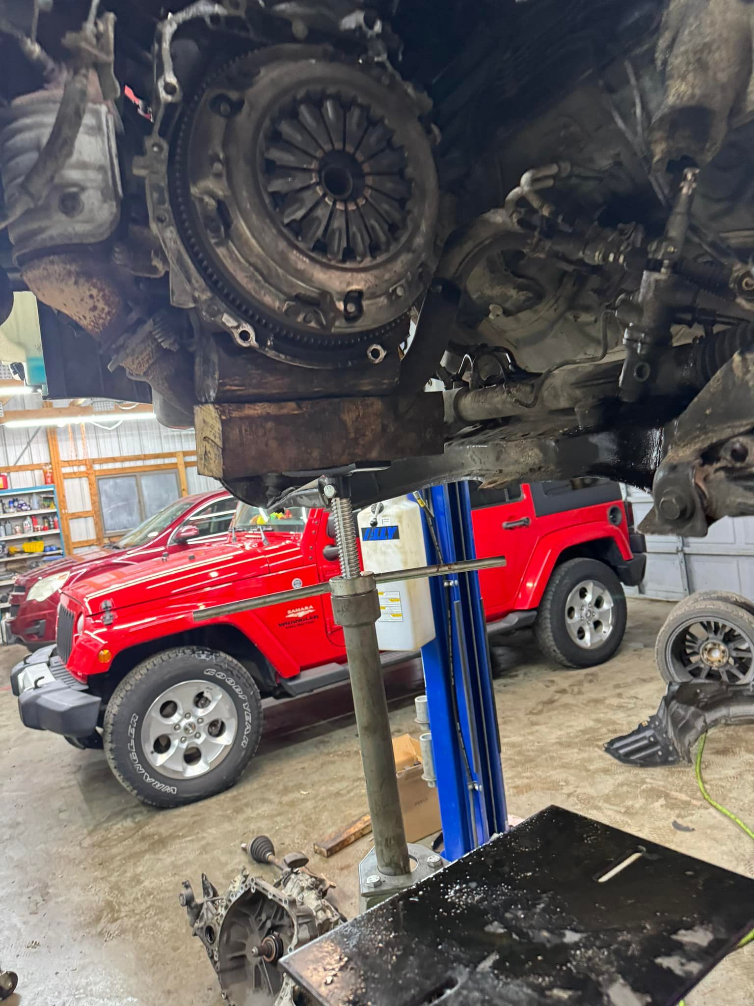 Red Jeep On Hydraulic Lift For Suspension Service | Greenfield Auto Repair