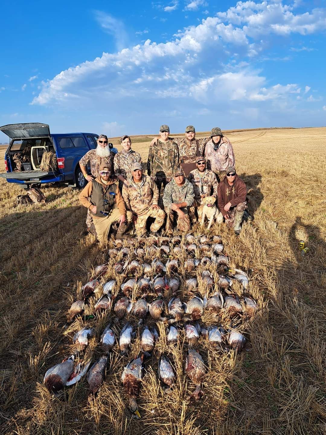 A group of hunters are posing for a picture in a field.