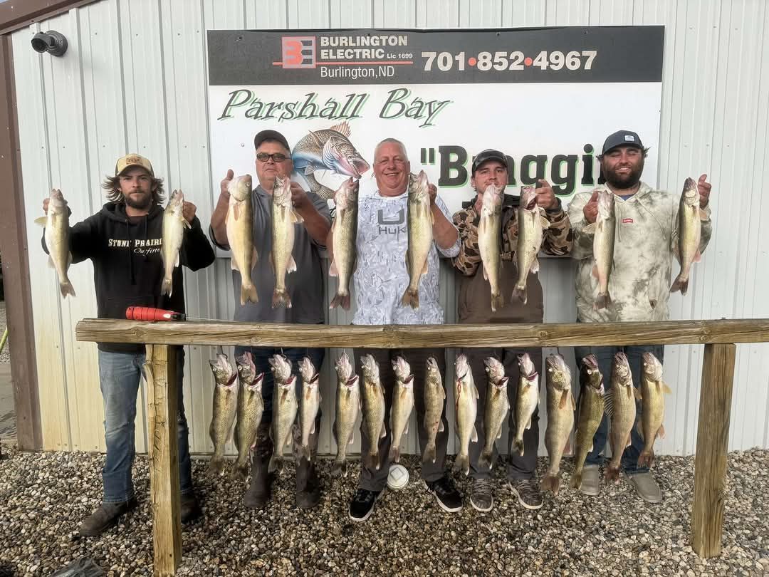 A group of men are standing next to each other holding fish in front of a building.