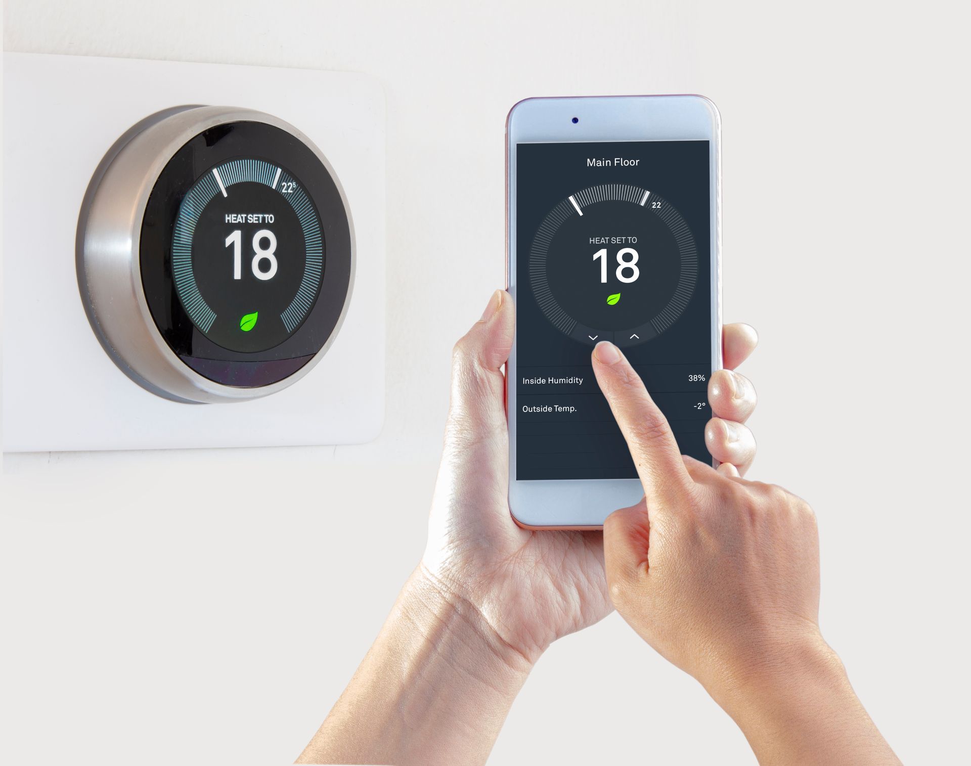 Person using a smartphone to control a smart thermostat; both show a temperature of 18 degrees.