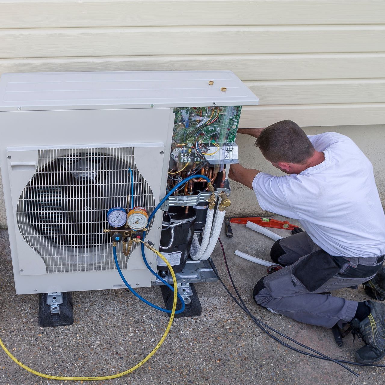 A man is working on an air conditioner outside of a building.