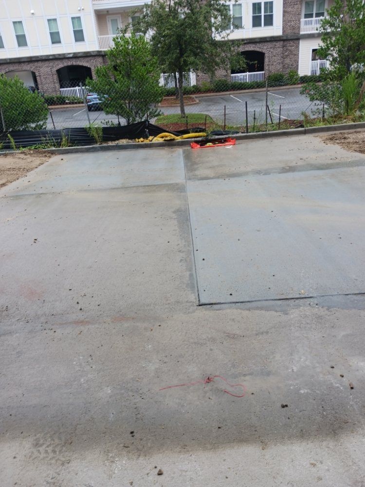 Concrete parking lot with a low barrier in front of an apartment building.