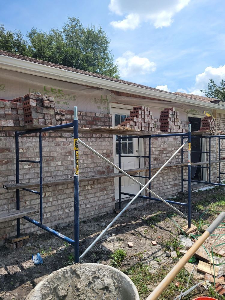 Scaffolding supports bricklaying on a building's side. Bricks, mortar, and a wheelbarrow are visible.