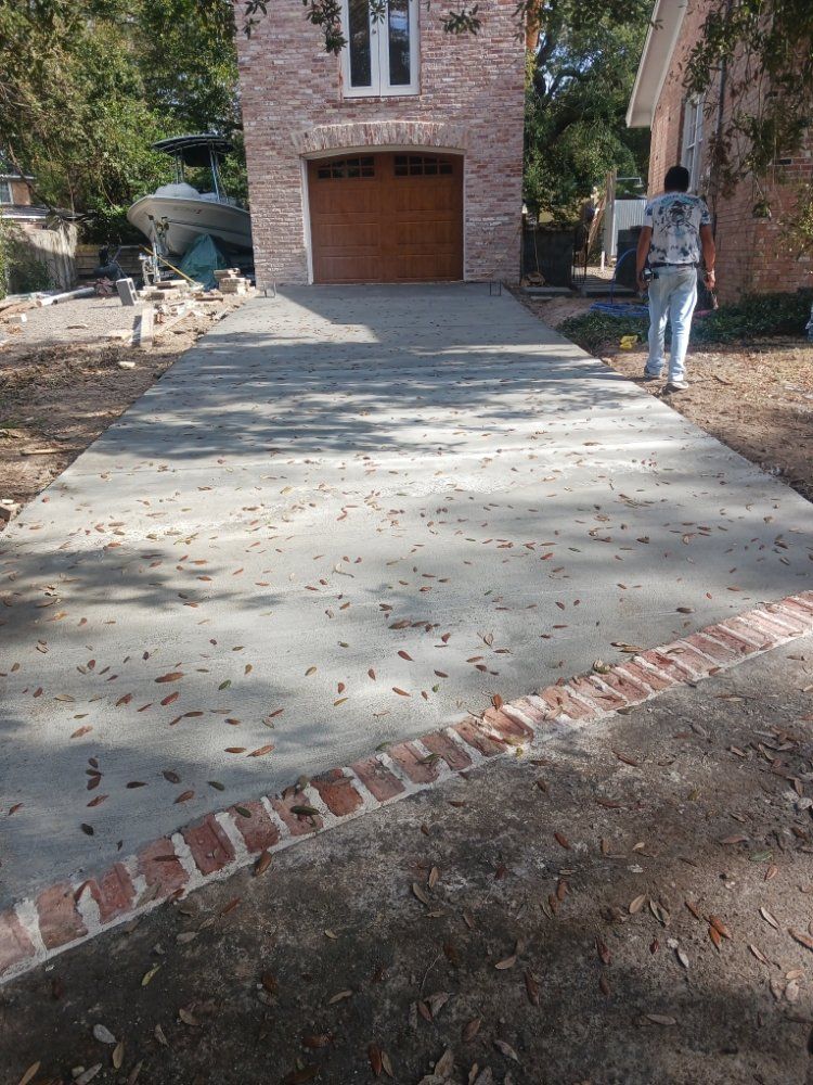 Concrete driveway leading to a brick garage. A person stands on the right side.