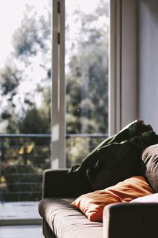 A couch with pillows on it is sitting in front of a window in a living room.