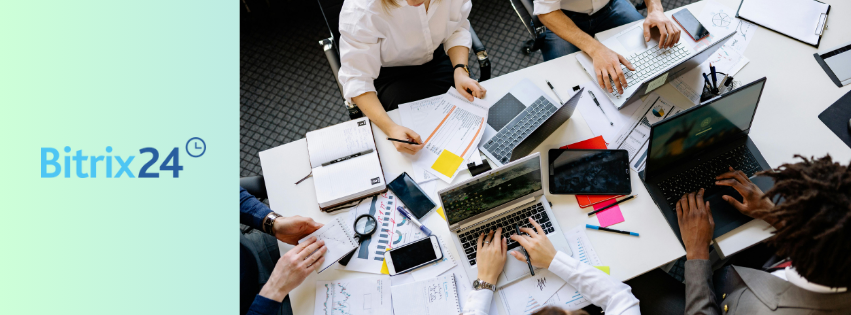 Grupo de personas trabajando con laptops y papeles; CRM Bitrix24 ayuda a organizar clientes y ventas