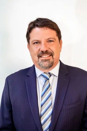 A man in a suit and tie is smiling for the camera.