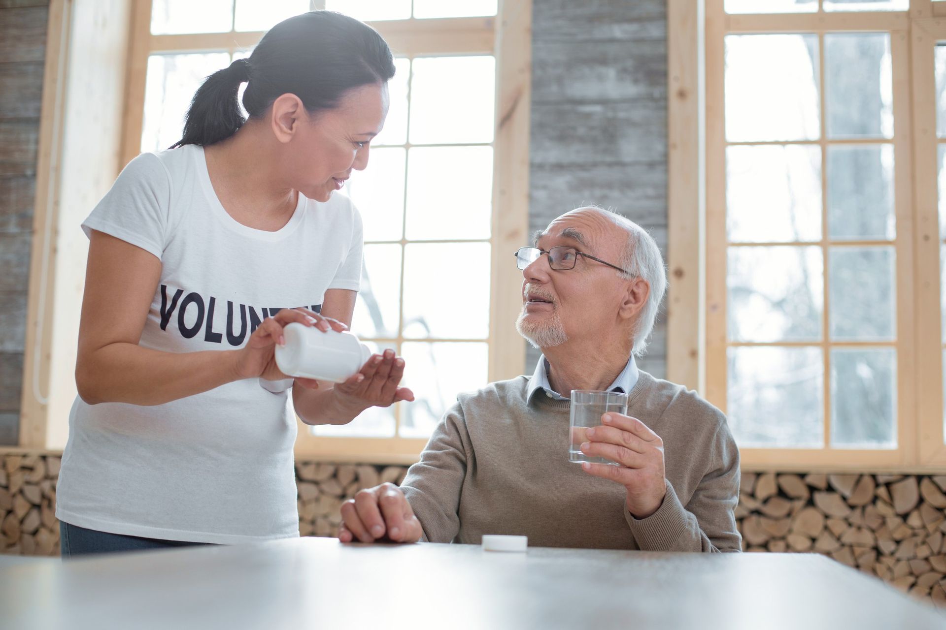 A woman is giving an elderly man a glass of water.