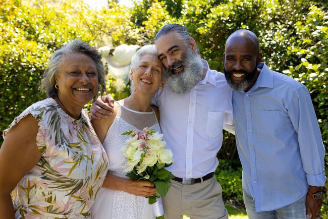 A bride and groom are posing for a picture with their parents.