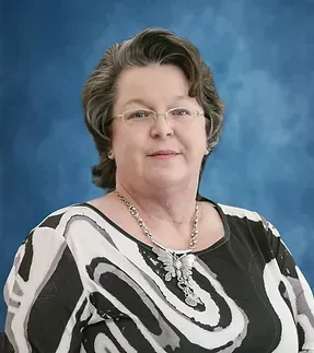 A woman wearing glasses and a black and white striped shirt is standing in front of a blue background.