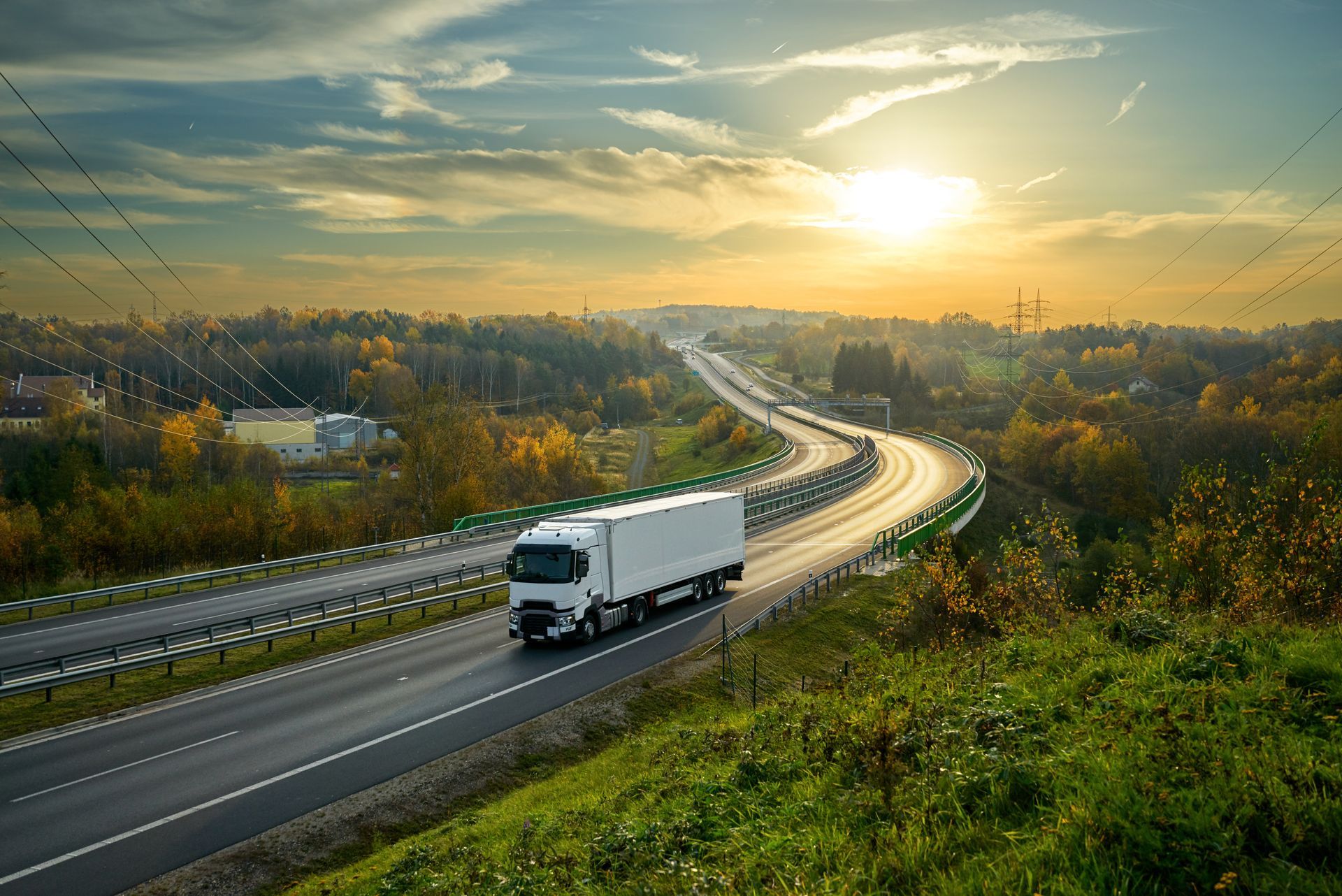 A white truck is driving down a highway at sunset