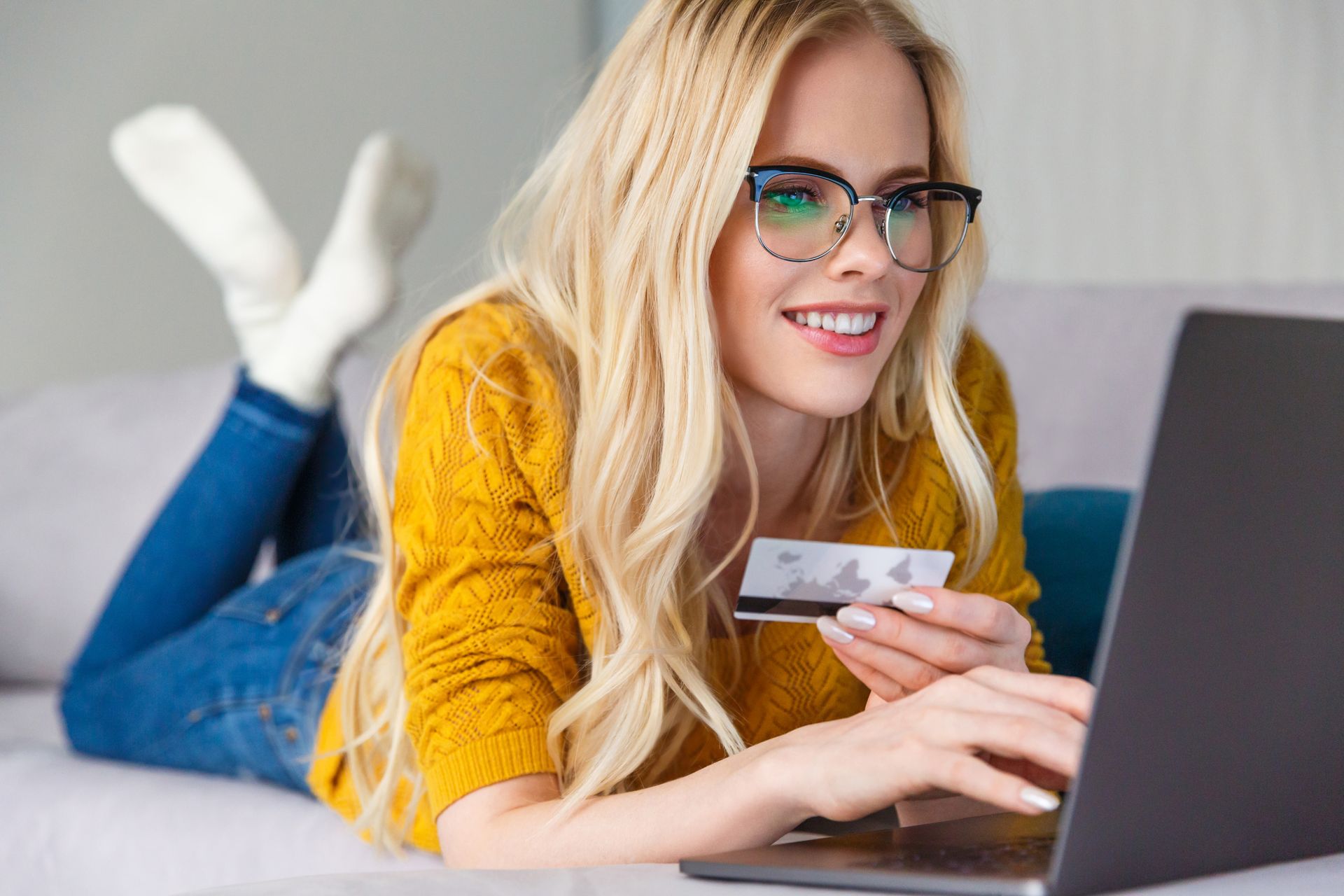a woman is using a laptop while holding a credit card