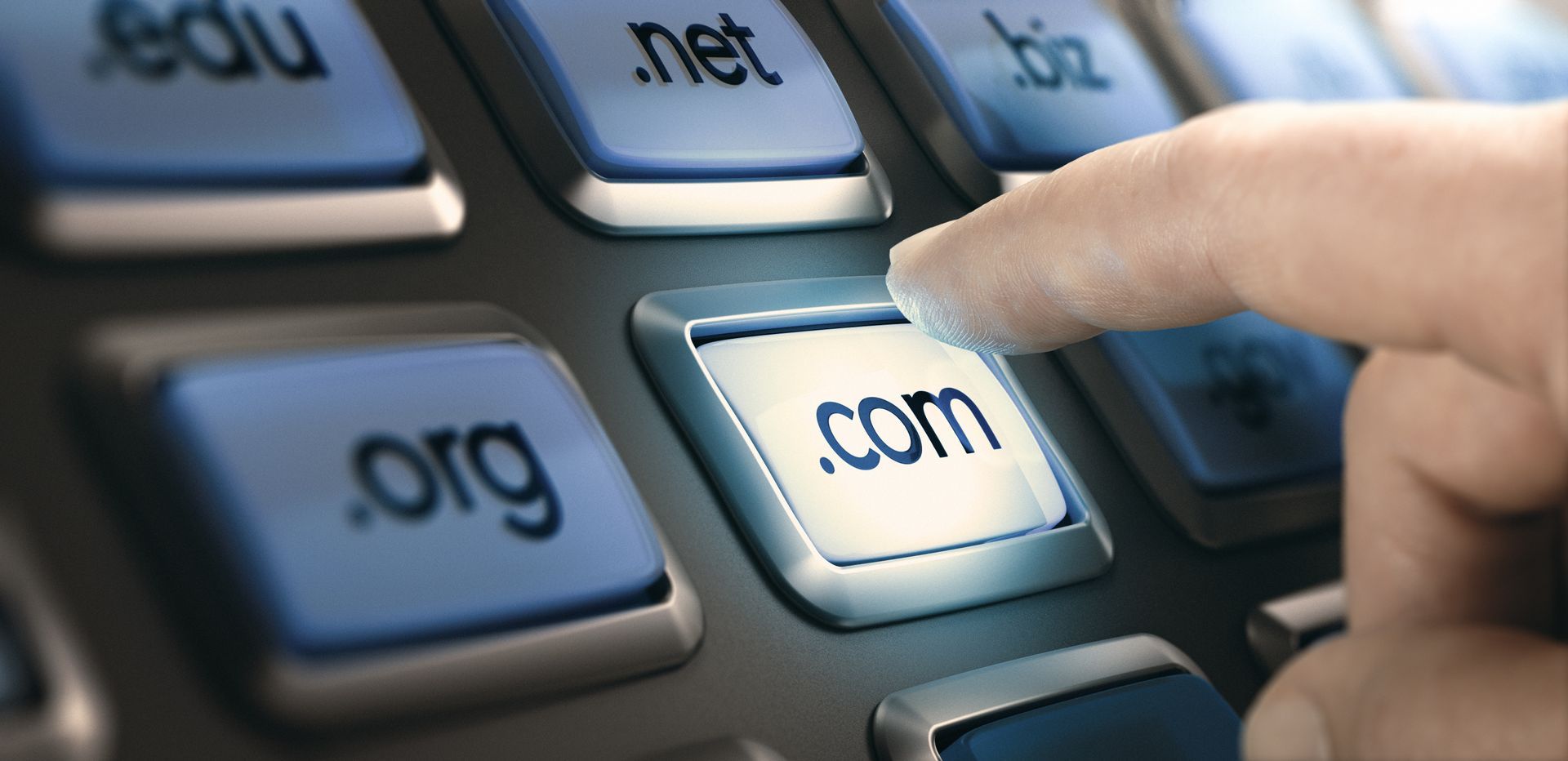 a person is pressing the .com button on a keyboard to register a domain name