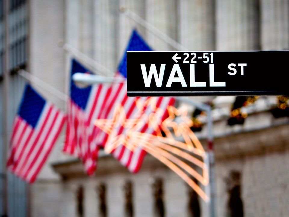 A wall street sign with american flags in the background