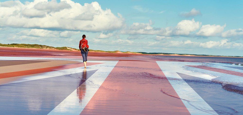 A person in a red jacket is walking on a wet road