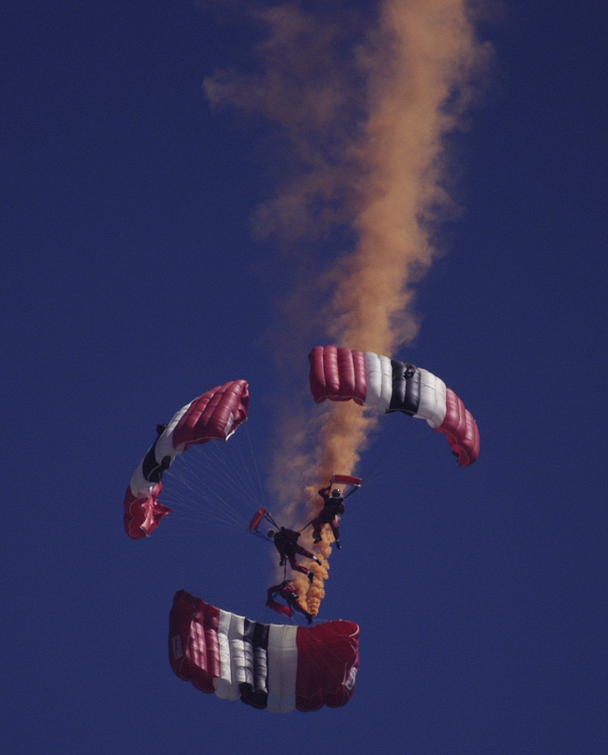 A person is flying through the air with a red white and blue parachute