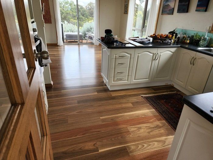 A kitchen with hardwood floors and white cabinets