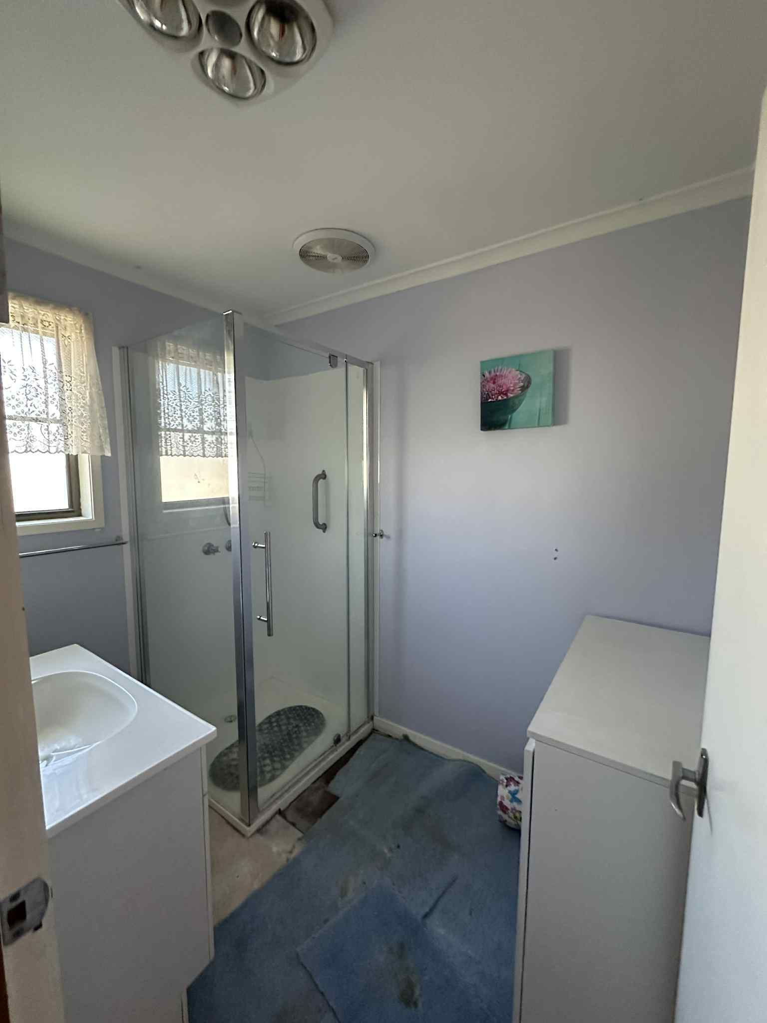 A bathroom featuring a shower stall, a white vanity with a sink, a dresser, and lavender-colored walls.
