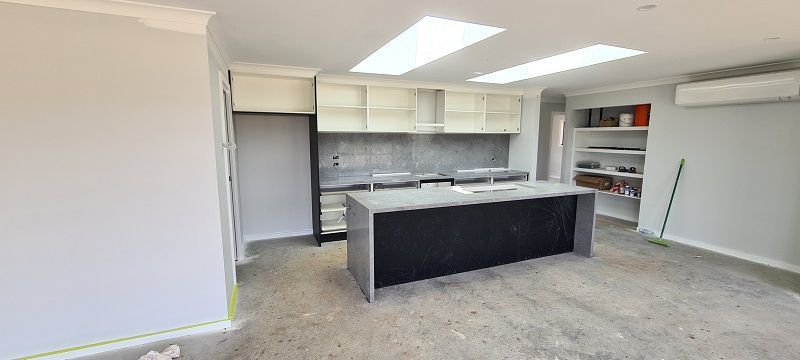 An empty kitchen with a large island in the middle of the room.