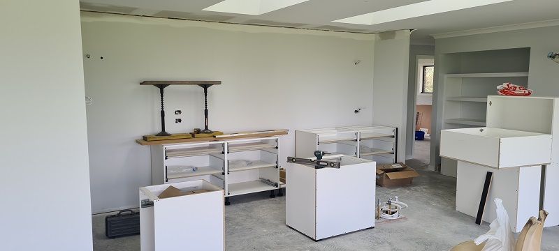 A room with a lot of white cabinets and boxes on the floor.