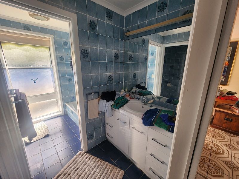 A bathroom with blue tiles , a sink and a mirror.