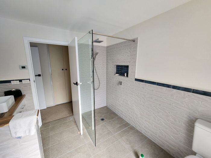 A bathroom with a walk in shower and a toilet.