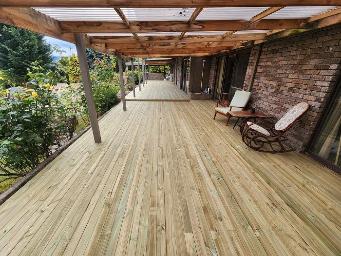 A large wooden deck with a clear roof and rocking chairs.