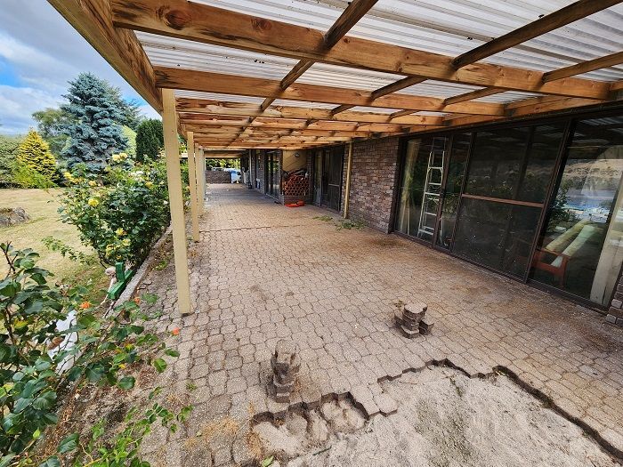 A patio with a wooden roof and a few cats on it.