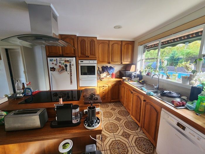 A kitchen with wooden cabinets , a stove top oven , a dishwasher , and a sink.