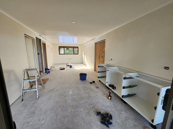 A room with white cabinets and a ladder in it.