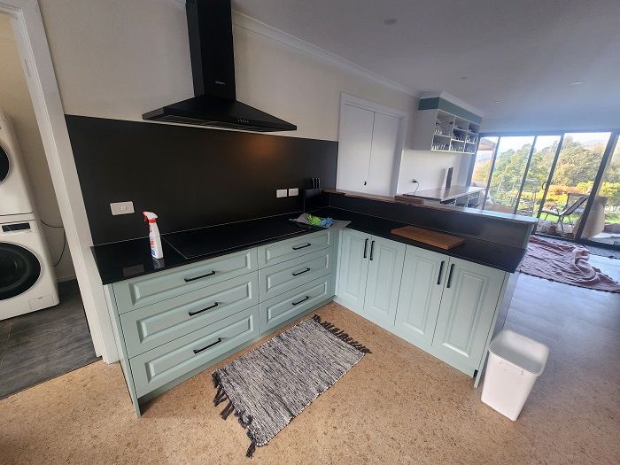 A kitchen with blue cabinets and black counter tops.