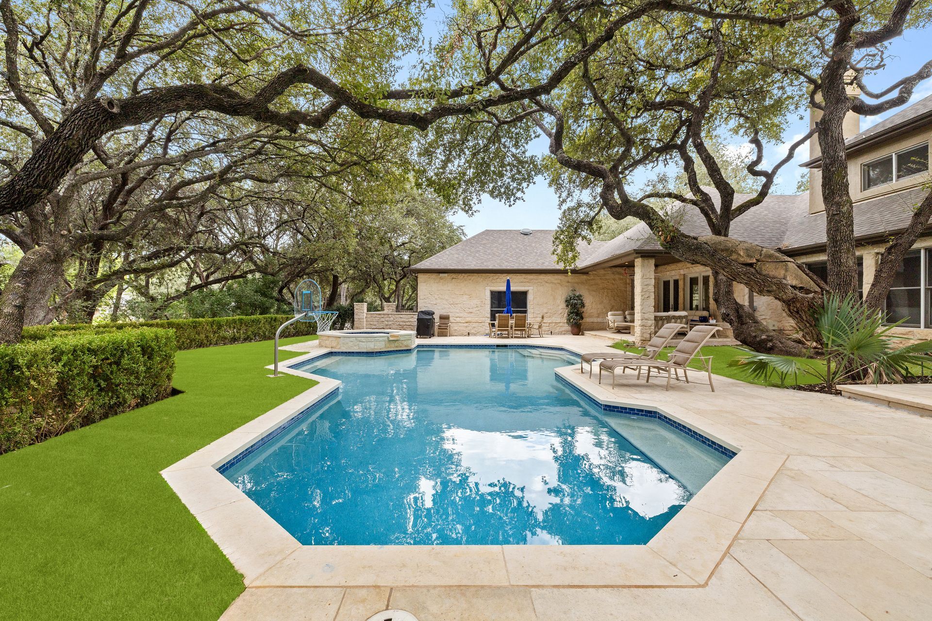 A large swimming pool in the backyard of a house surrounded by trees.