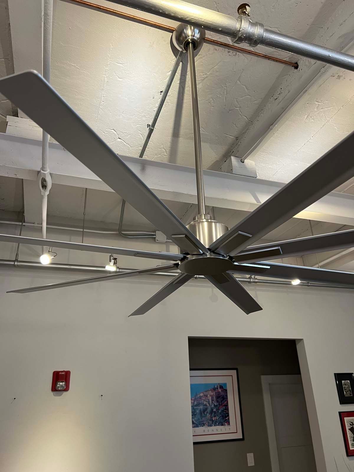 A large ceiling fan is hanging from the ceiling of a room.