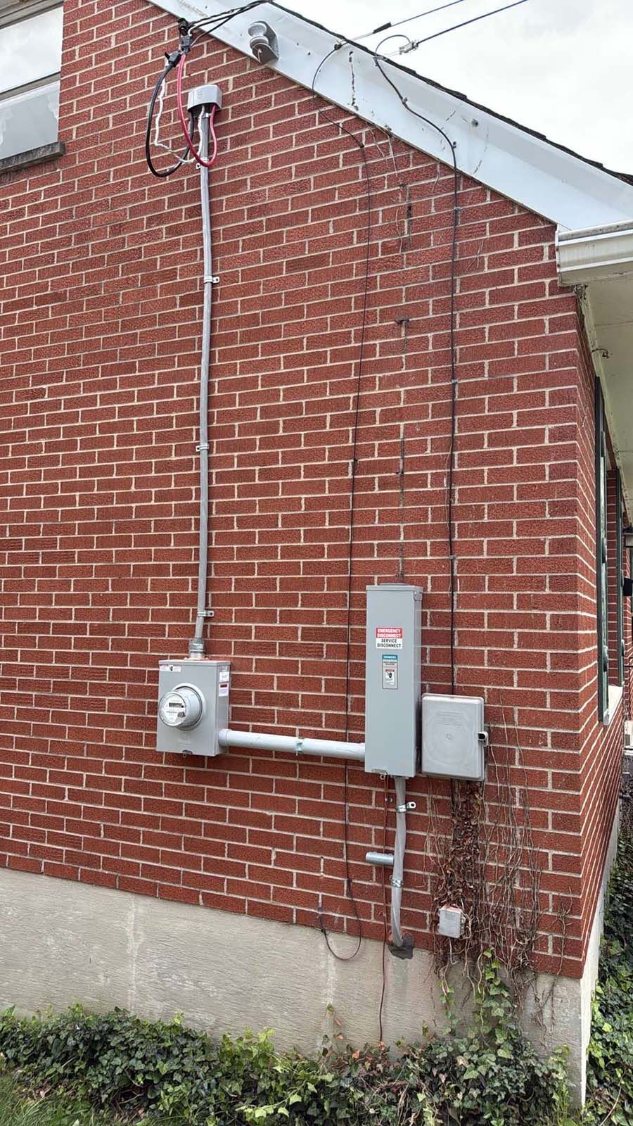 A brick house with a electrical box on the side of it.