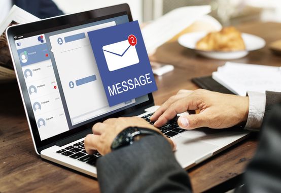 Person typing on laptop, receiving two new message notifications on screen.