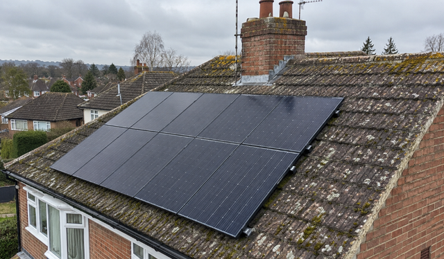 Solar panels on an old, moss-covered tiled roof
