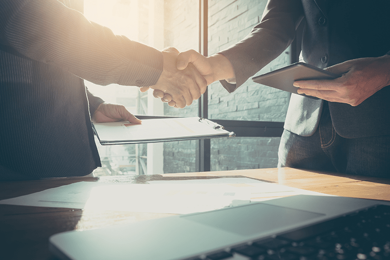 A man and a woman are shaking hands over a table.