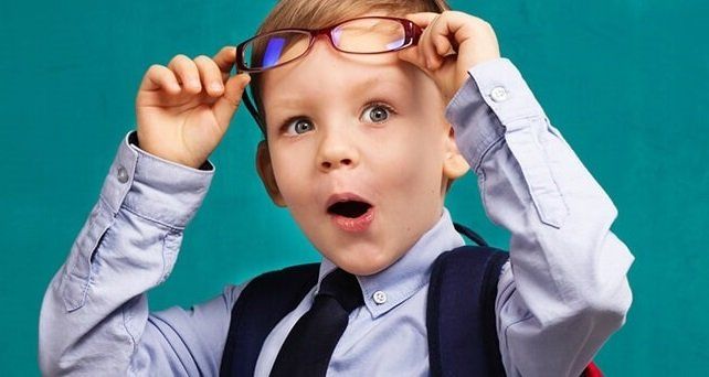 bambino che solleva gli occhiali da vista