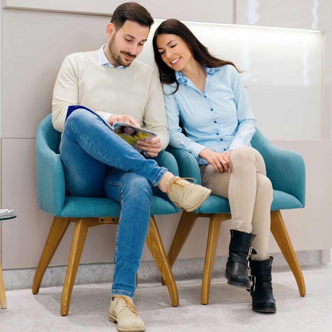 A man and a woman are sitting in chairs in a waiting room.