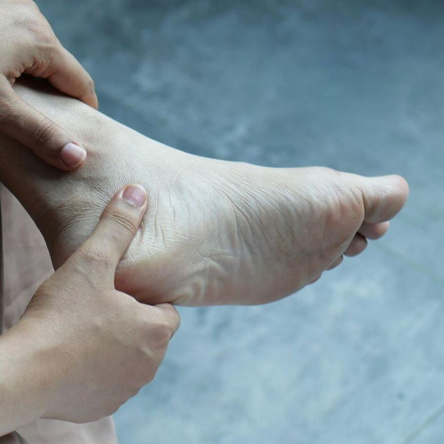 A person is touching their foot with their fingers
