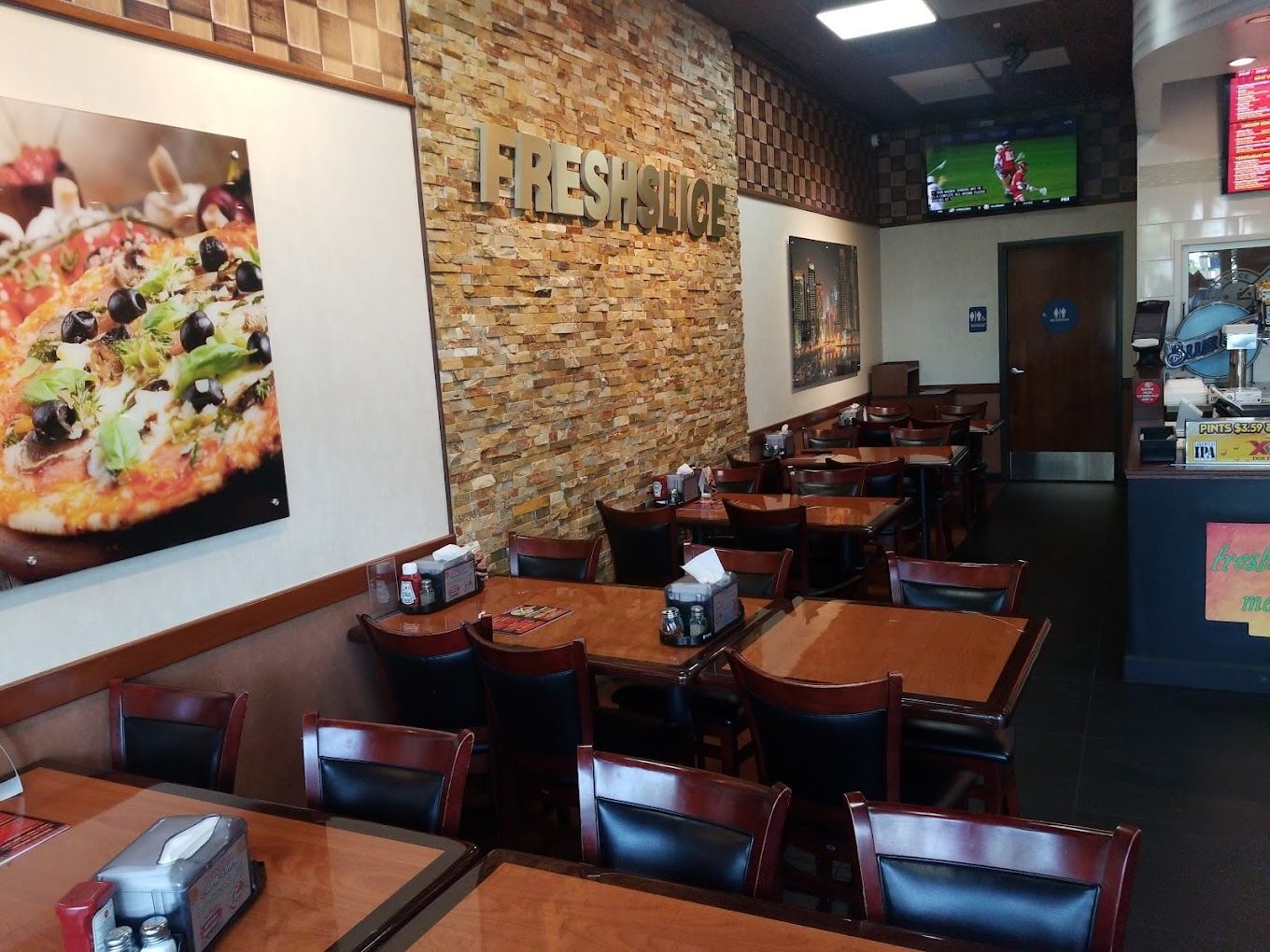 A restaurant with tables and chairs and a picture of a pizza on the wall.