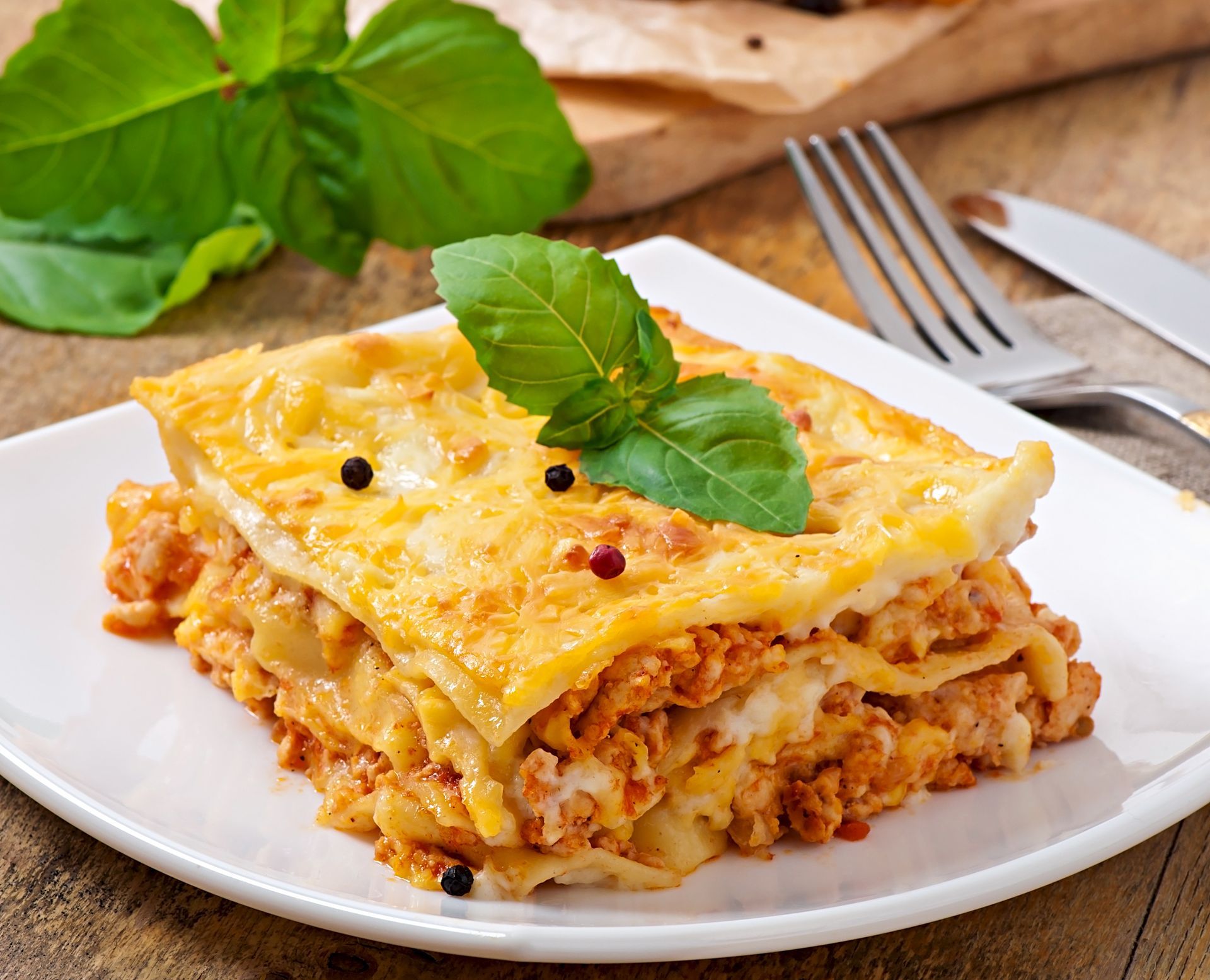 A slice of lasagna is on a white plate with a fork.