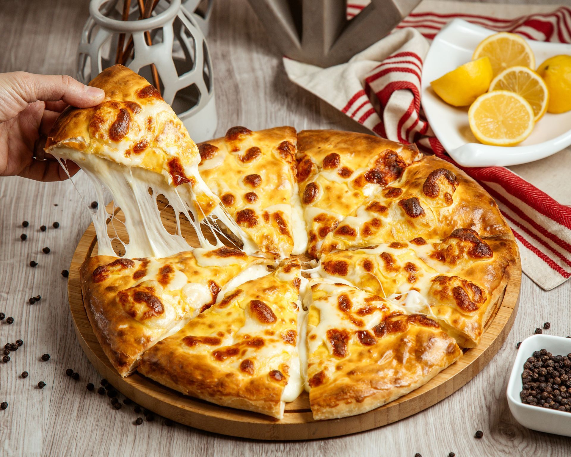 A person is taking a slice of cheese pizza from a pizza on a wooden cutting board.