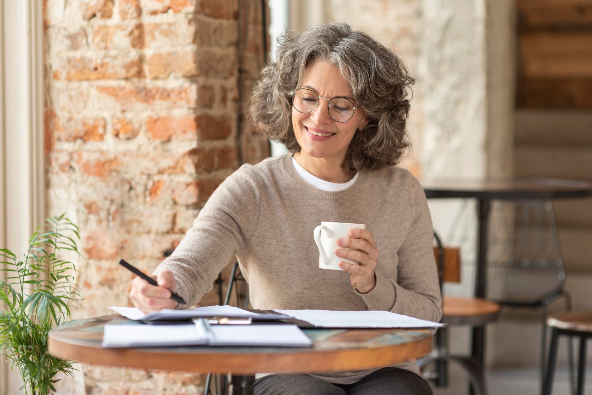 Two women are sitting at a table with laptops and papers.