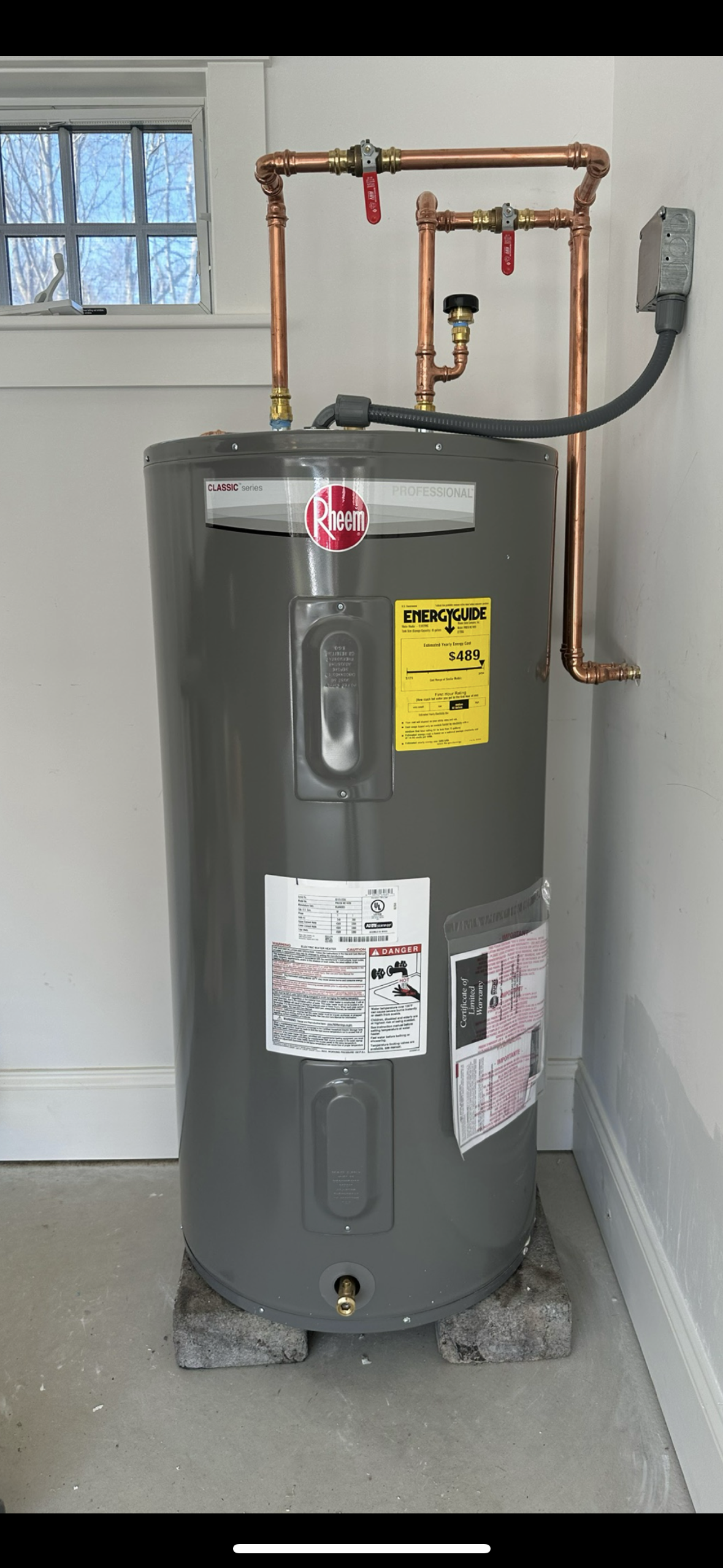 A water heater is sitting in a room next to a window.