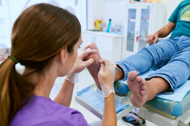 A woman is curing a patient's callus in a clinic.
